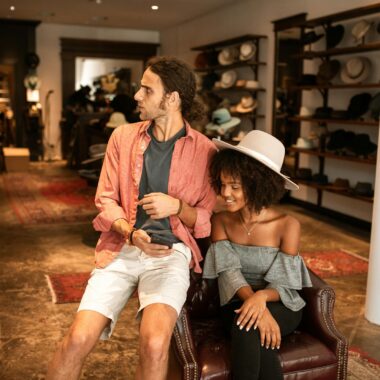 A man and woman enjoying shopping in a stylish boutique, surrounded by hats.