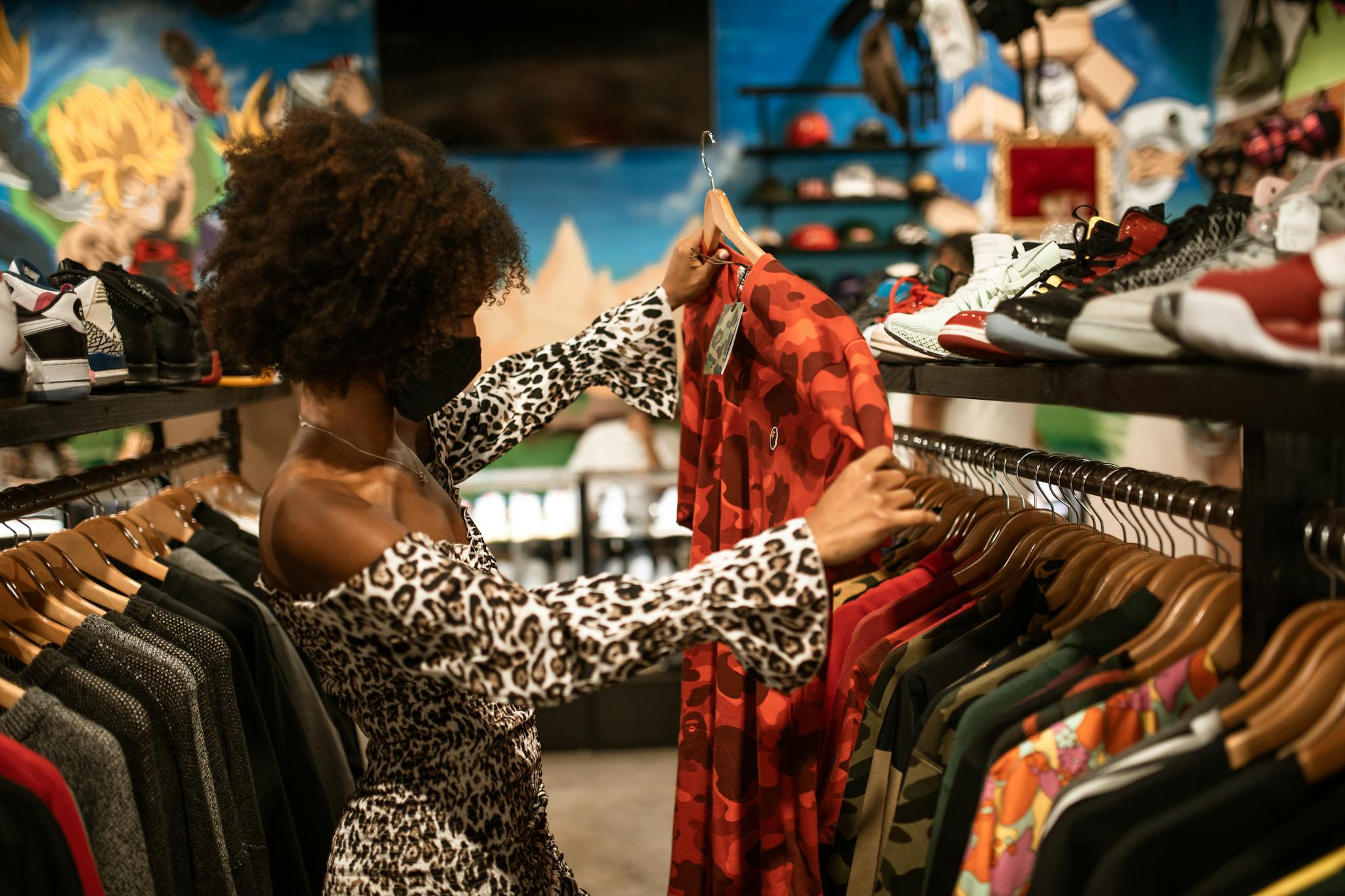 Young woman shops stylish clothing in boutique, wearing mask for safety.